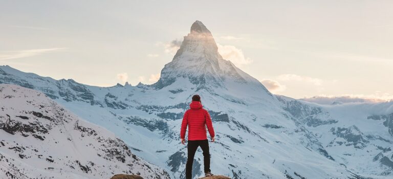 person in red hoodie standing on snowy mountain during daytime